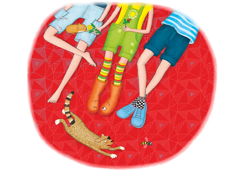 3 Kinder liegen vergnügt auf einer Decke, eine Katze jagt einer Biene hinterher